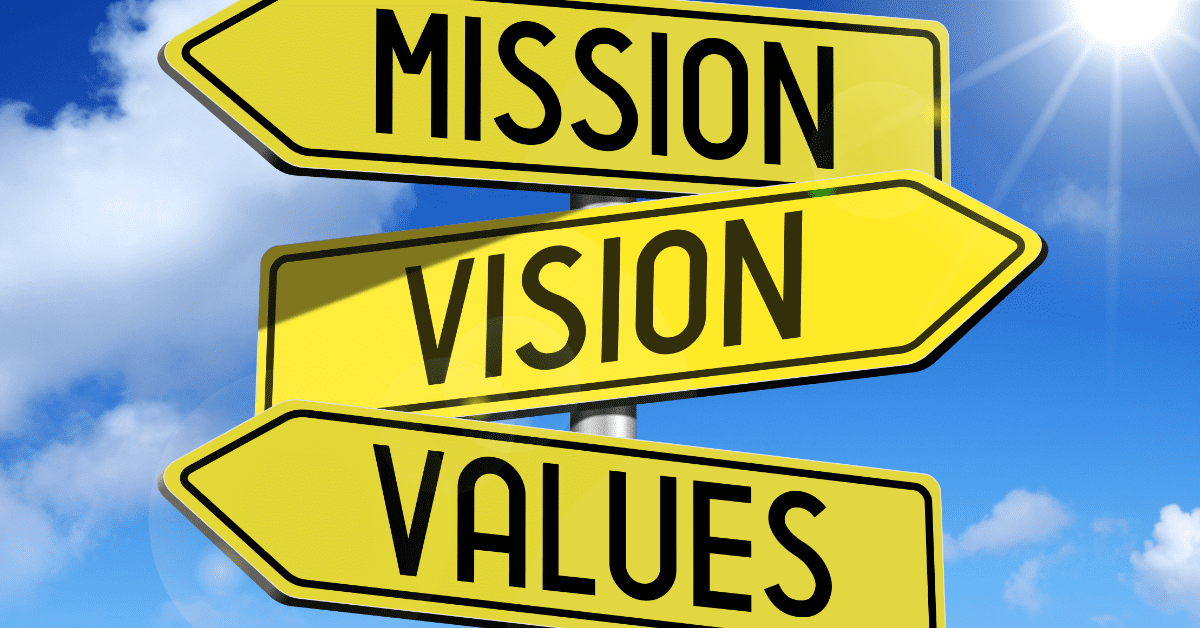 Mission, Vision, and Values displayed in all caps black text on yellow street signs